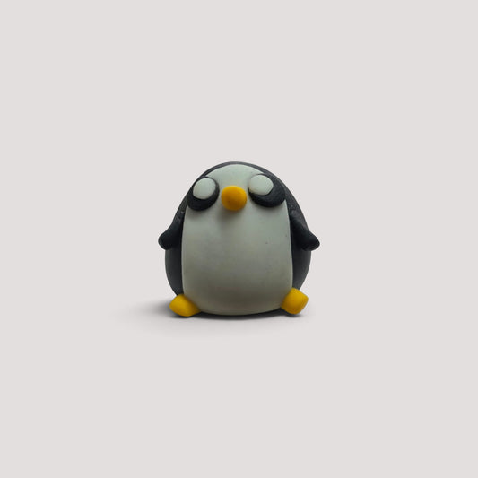 Statuetta artigianale di pinguino in pasta modellabile di El Muñequero Art con corpo bianco e nero e piedi gialli